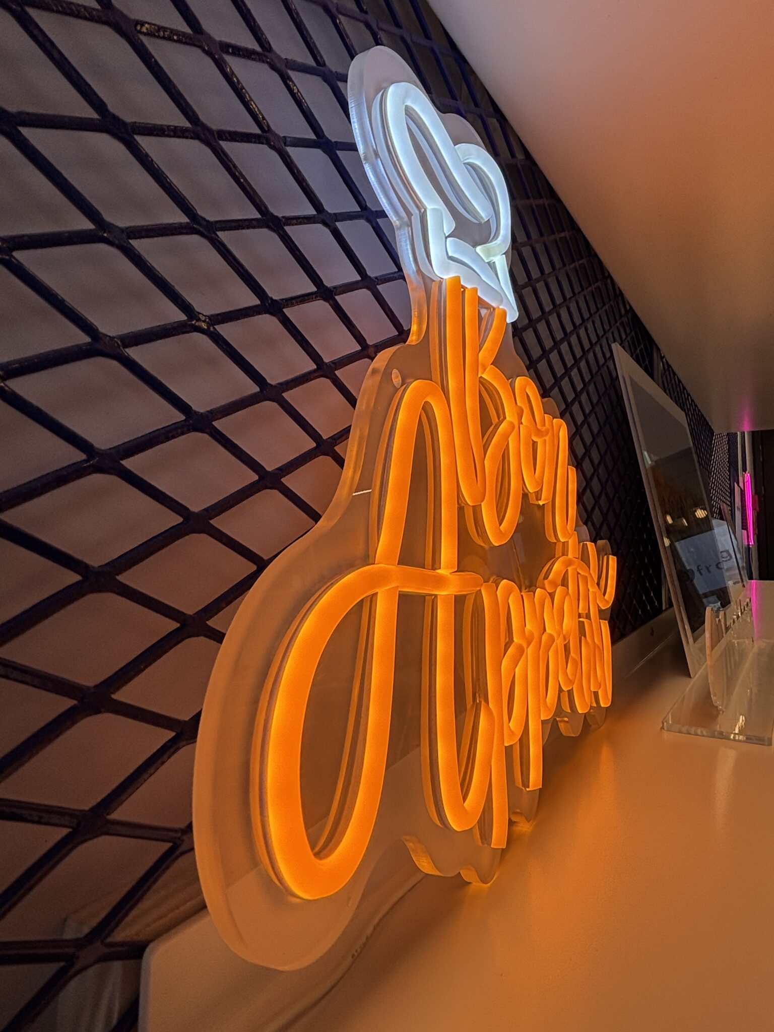 Orange Bon Appetit neon sign on a mesh wall