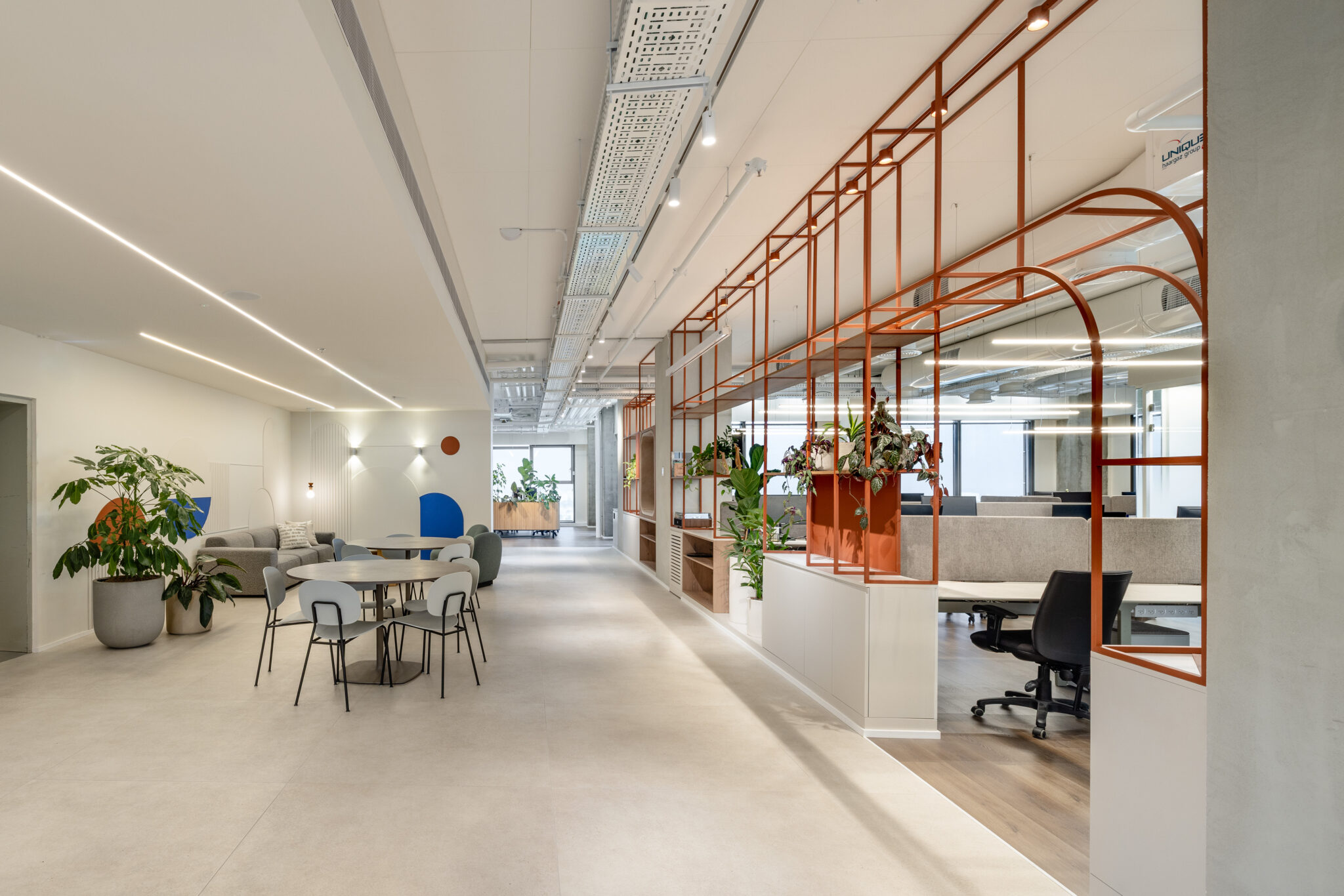 Open office with orange metal shelving frames and a dining area