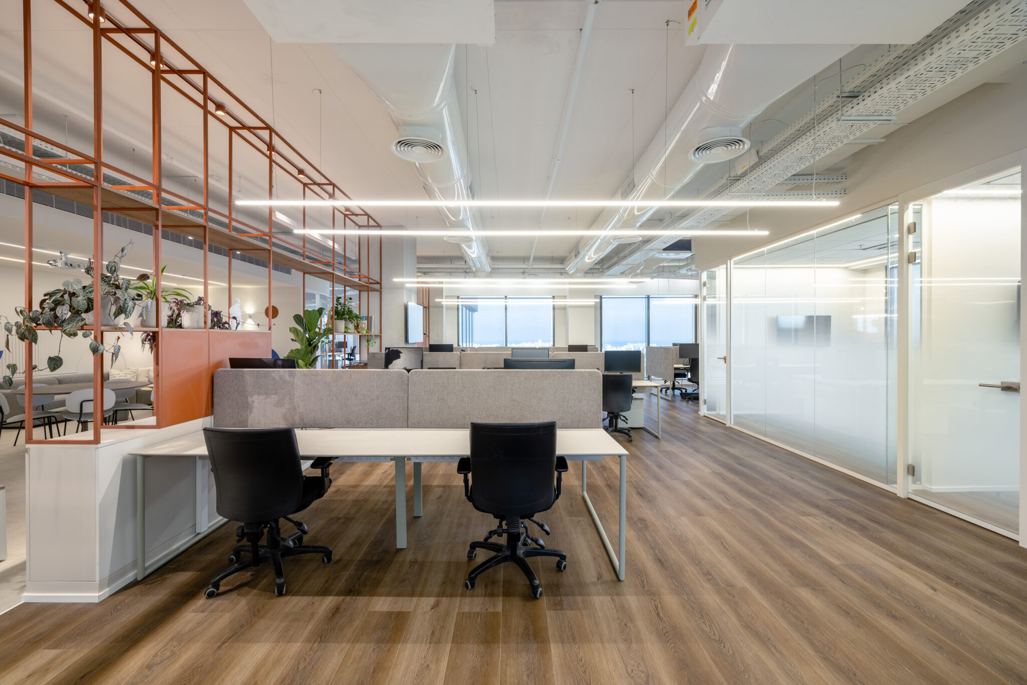 Workstations beside orange metal frame shelving with plants