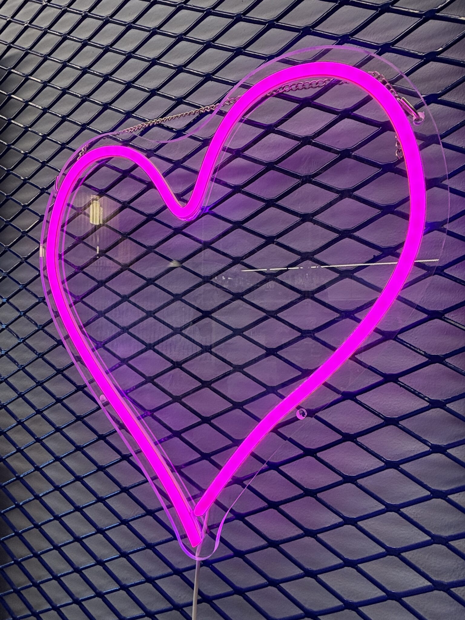 Pink neon heart on a mesh wall