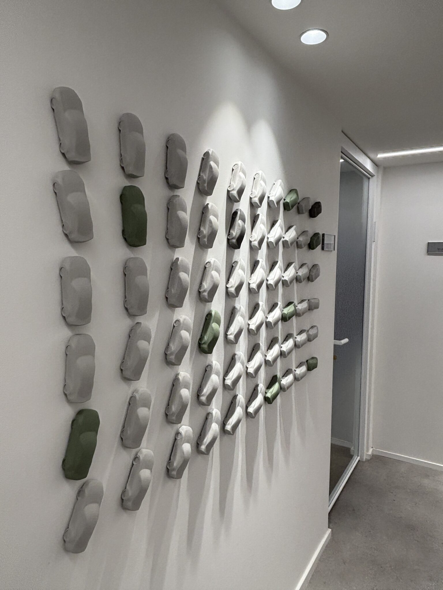 Grid of 3D grey and green car shapes on a corridor wall