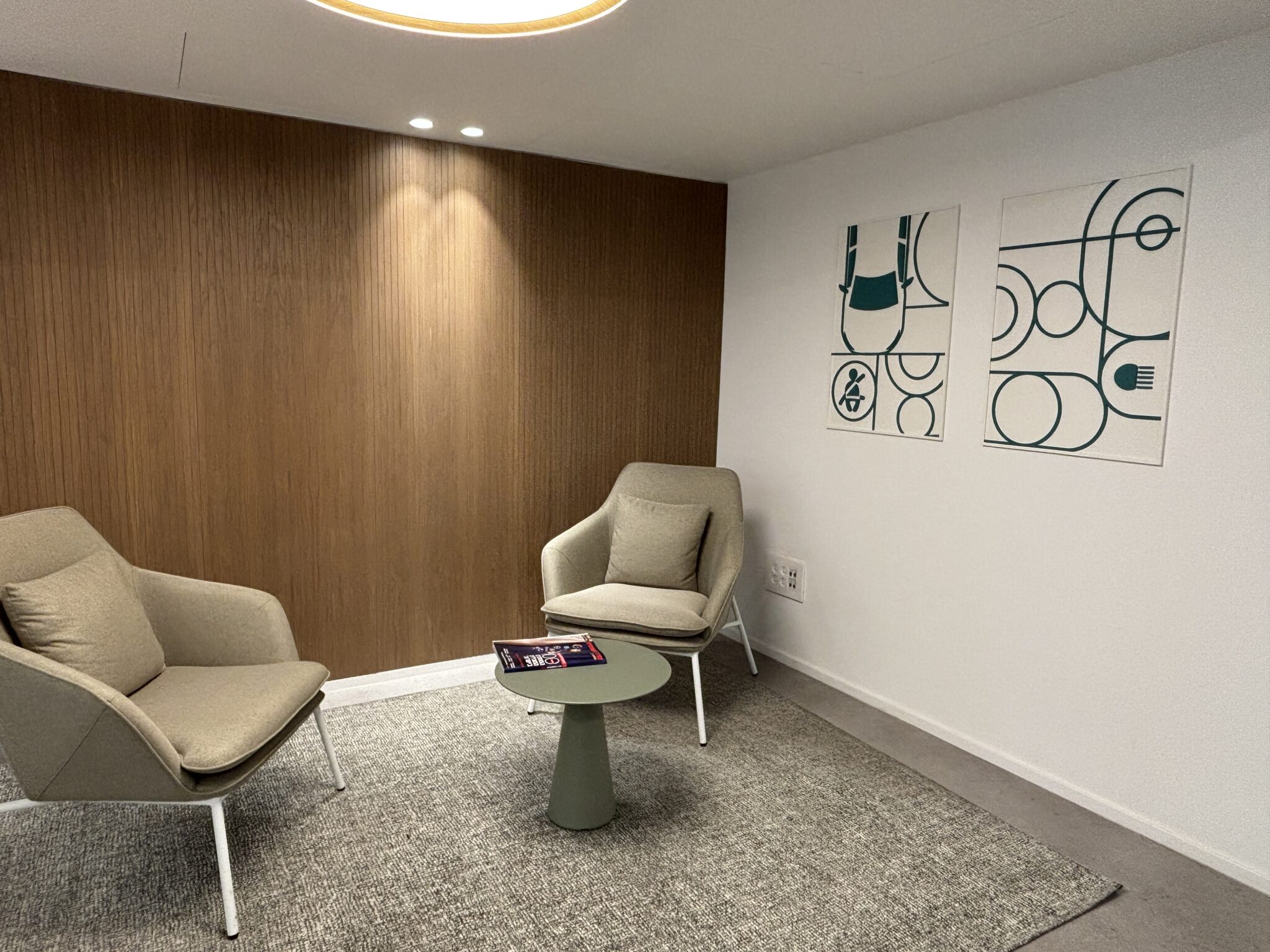 Waiting area with framed green line art prints and wood wall
