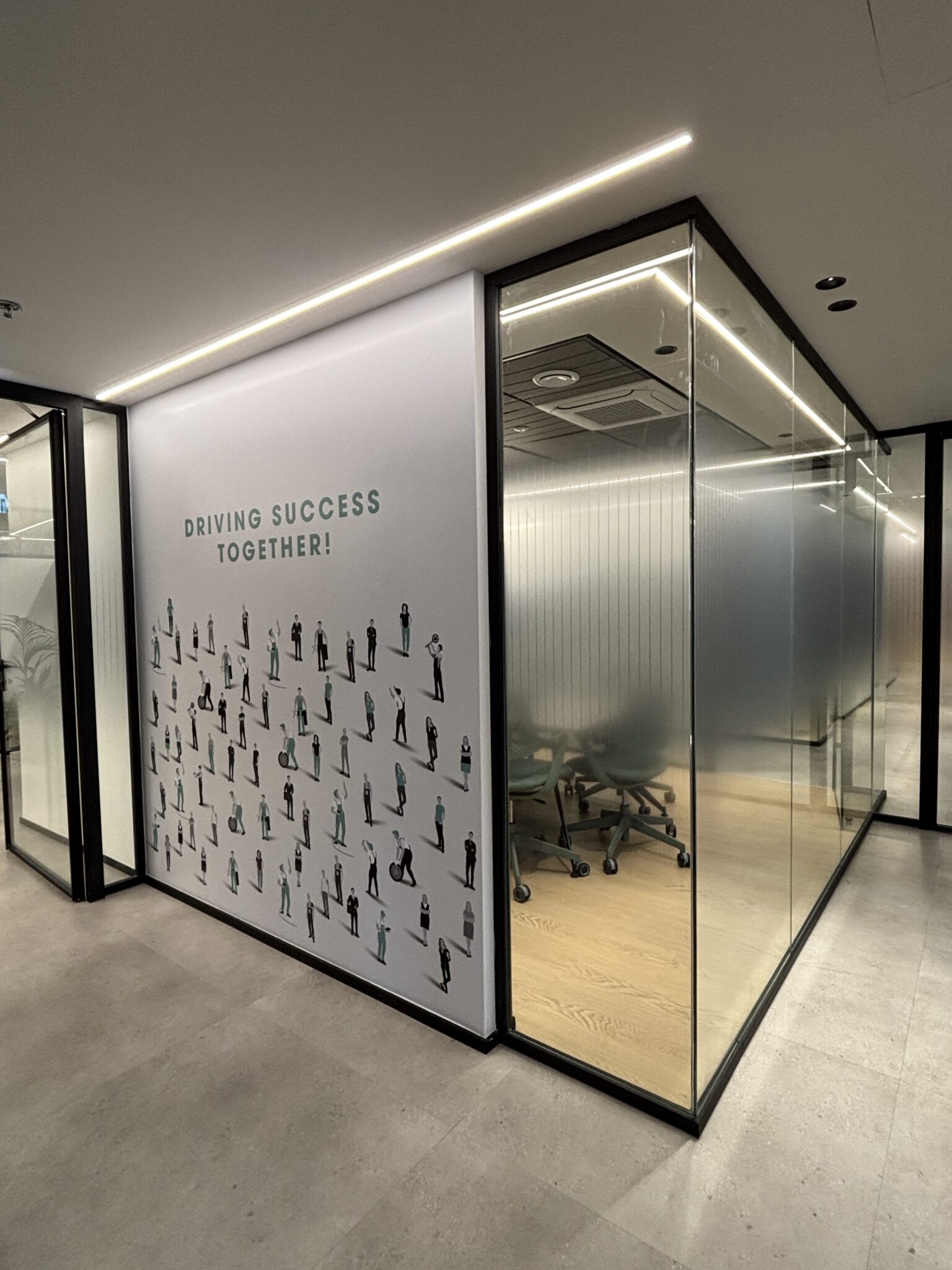 DRIVING SUCCESS TOGETHER wall graphic beside a glass meeting room