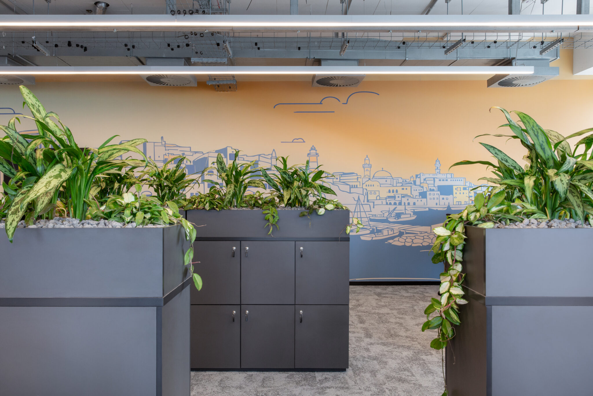 Planters and lockers in front of a city skyline wall mural
