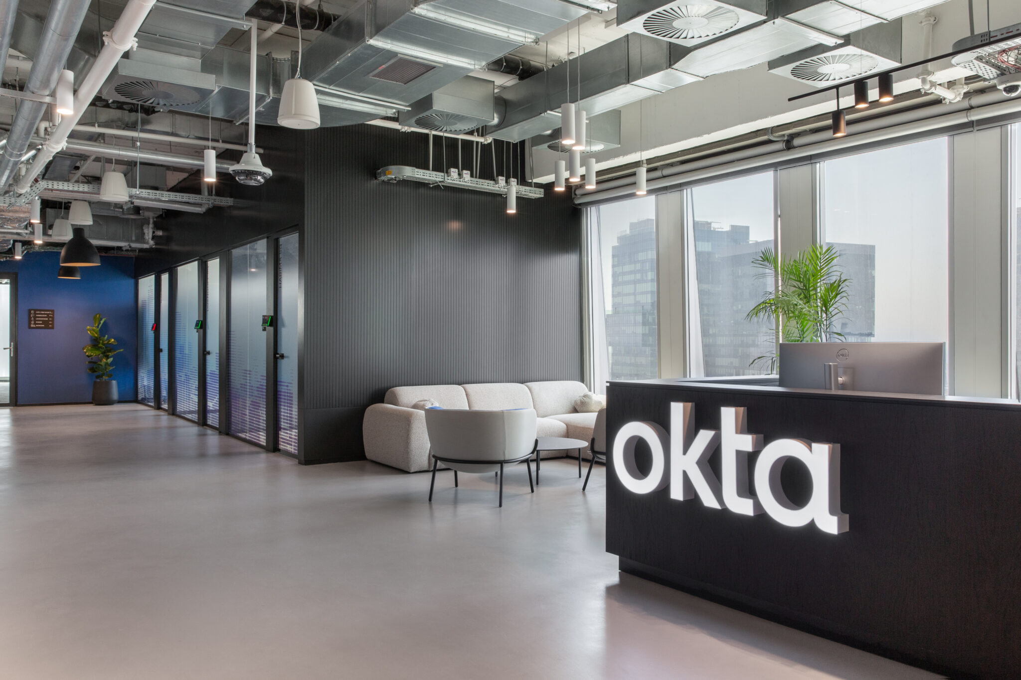 Lit okta logo on a black reception desk