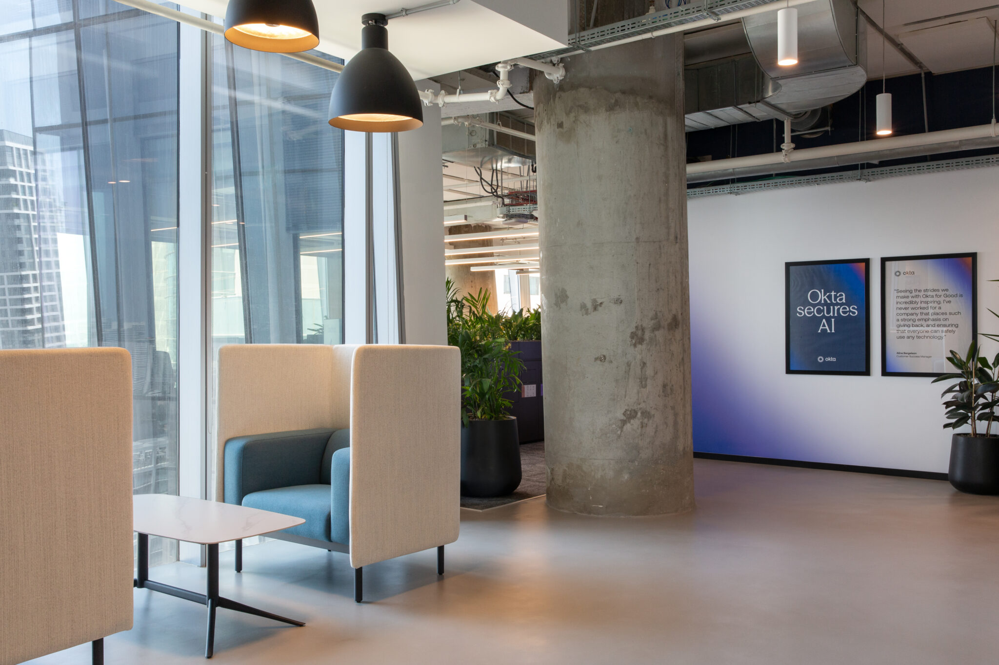 Booth seating by windows and Okta posters on a blue wall