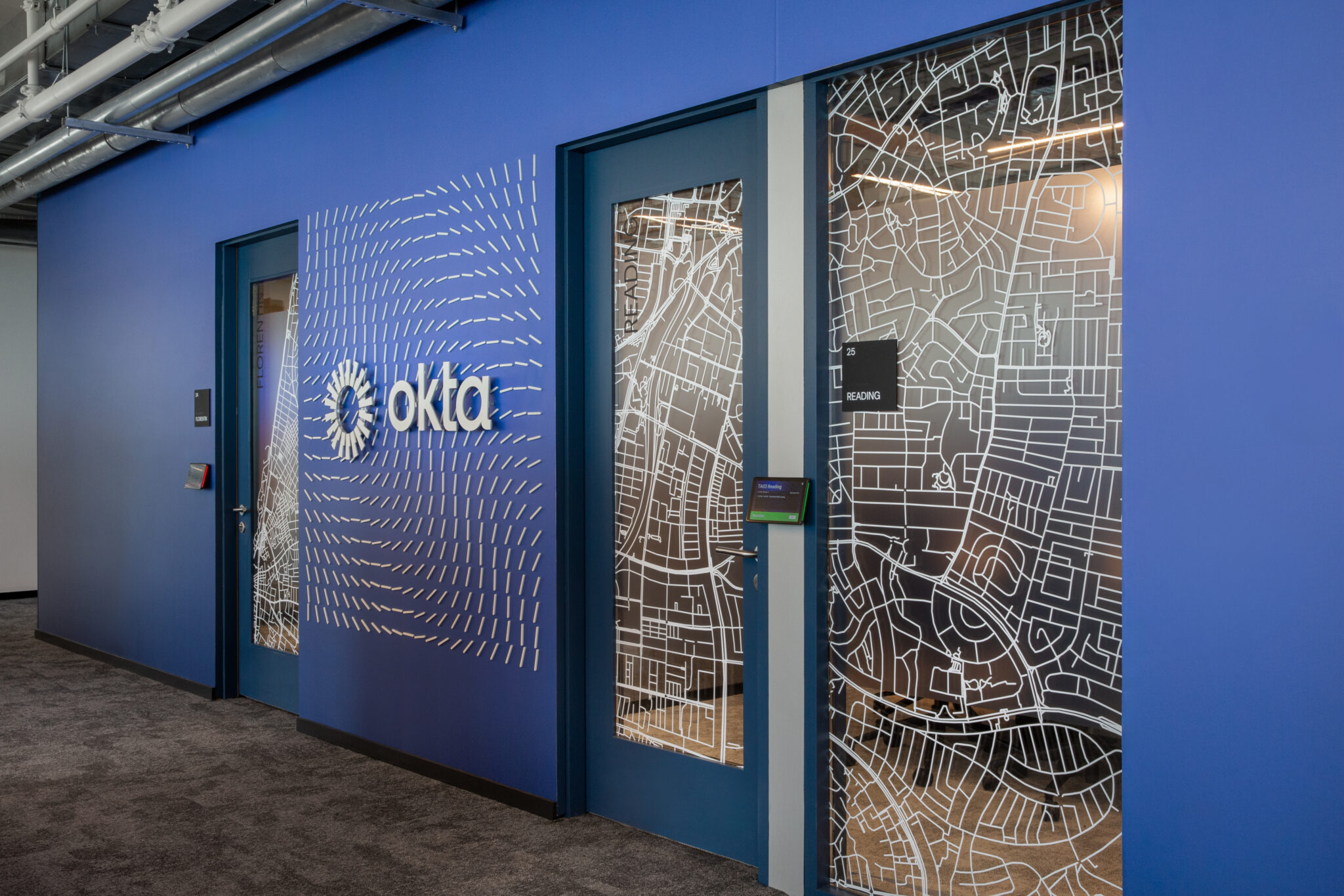 okta logo and white map pattern film on blue wall and glass doors