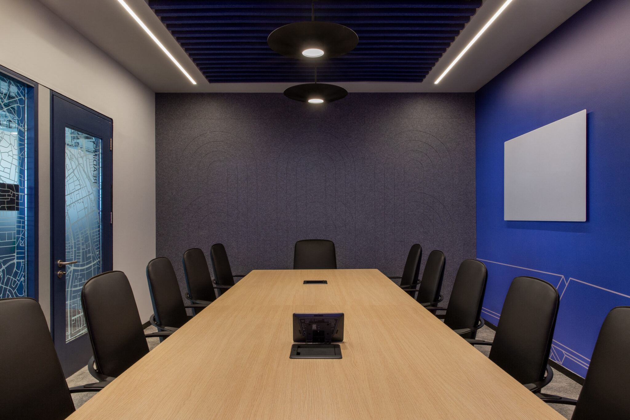 Boardroom with long wood table and a blue wall