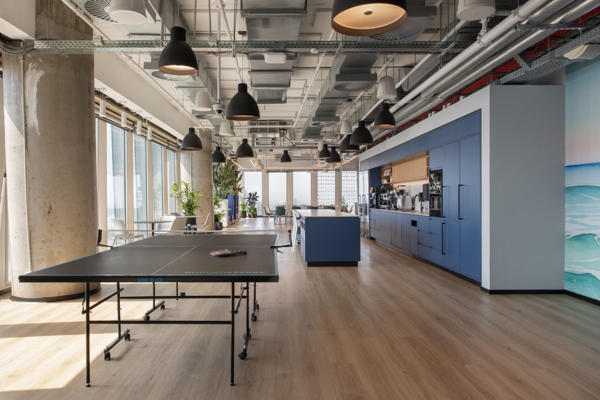 Office kitchen with blue cabinets and a ping pong table