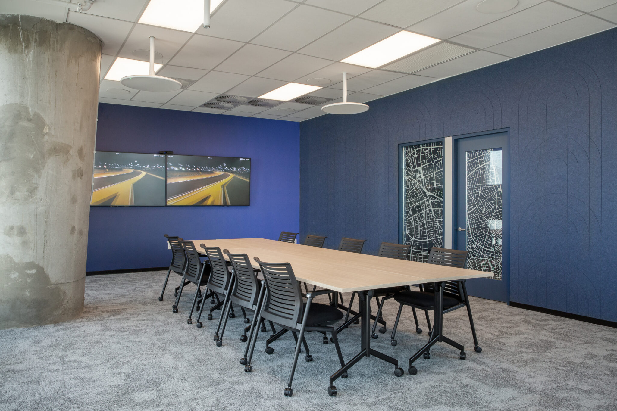 Boardroom with blue acoustic walls and a map pattern glass door