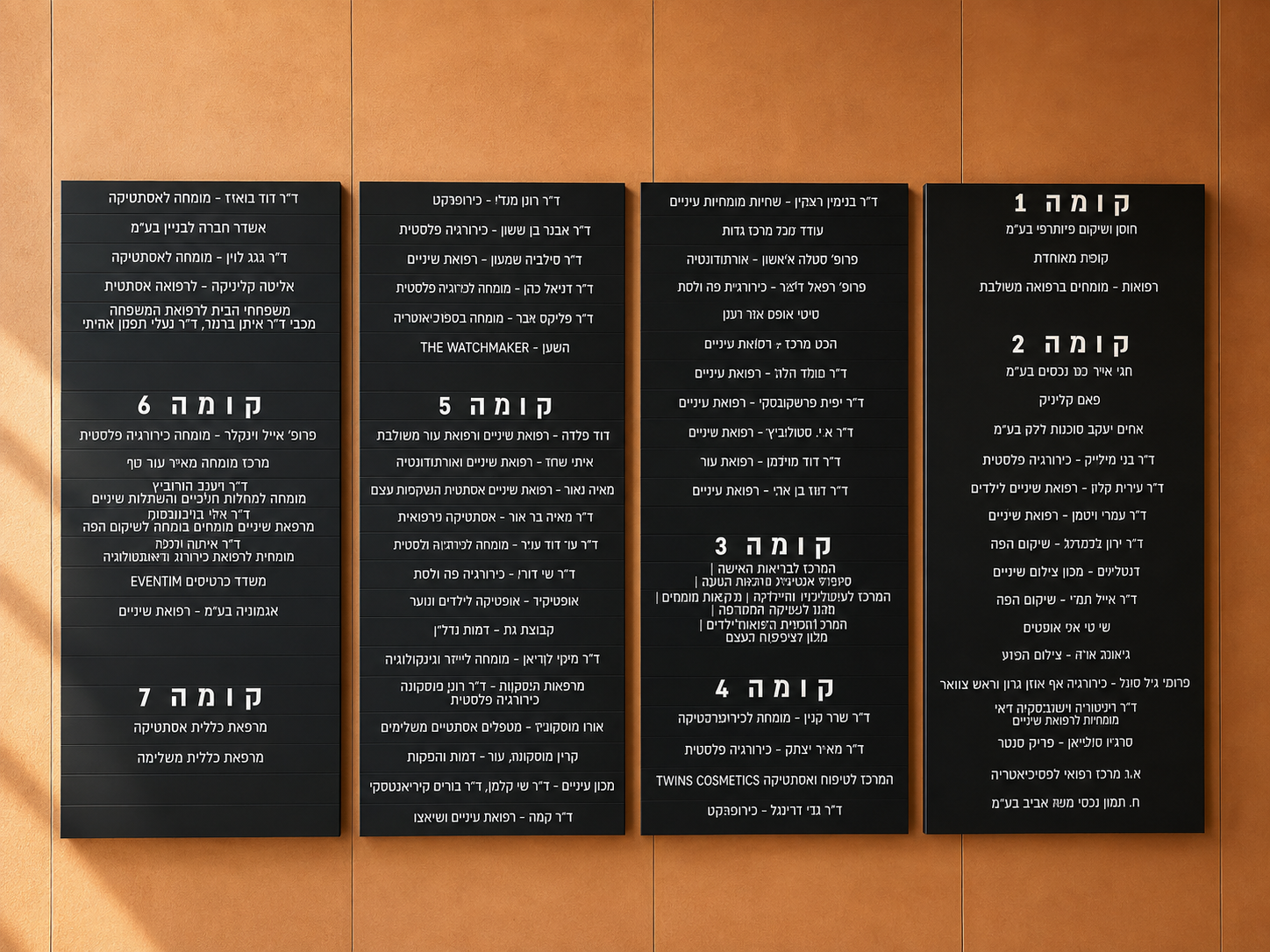 Black building directory signs listing floors in Hebrew