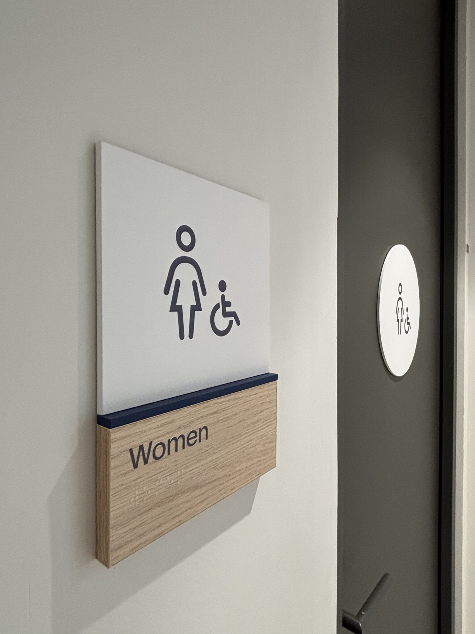 Women and accessible restroom sign with a wood nameplate