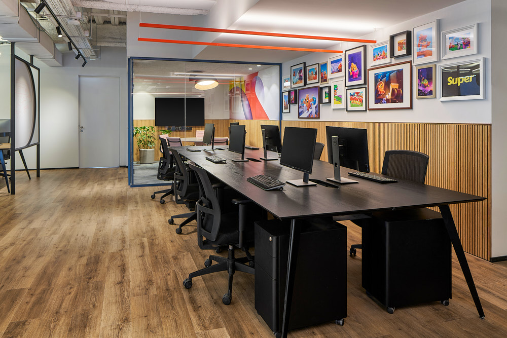 Open-plan desks beside a wall of framed colourful prints