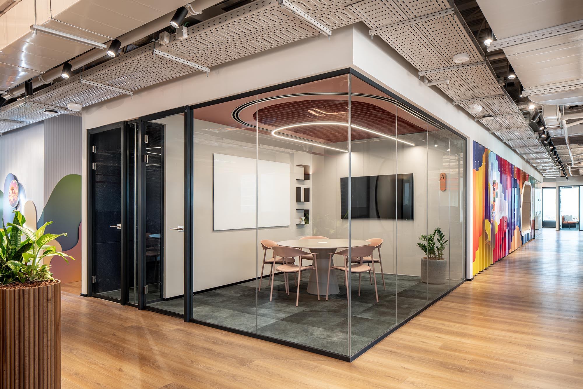 Glass meeting room with a colourful wall graphic beside it