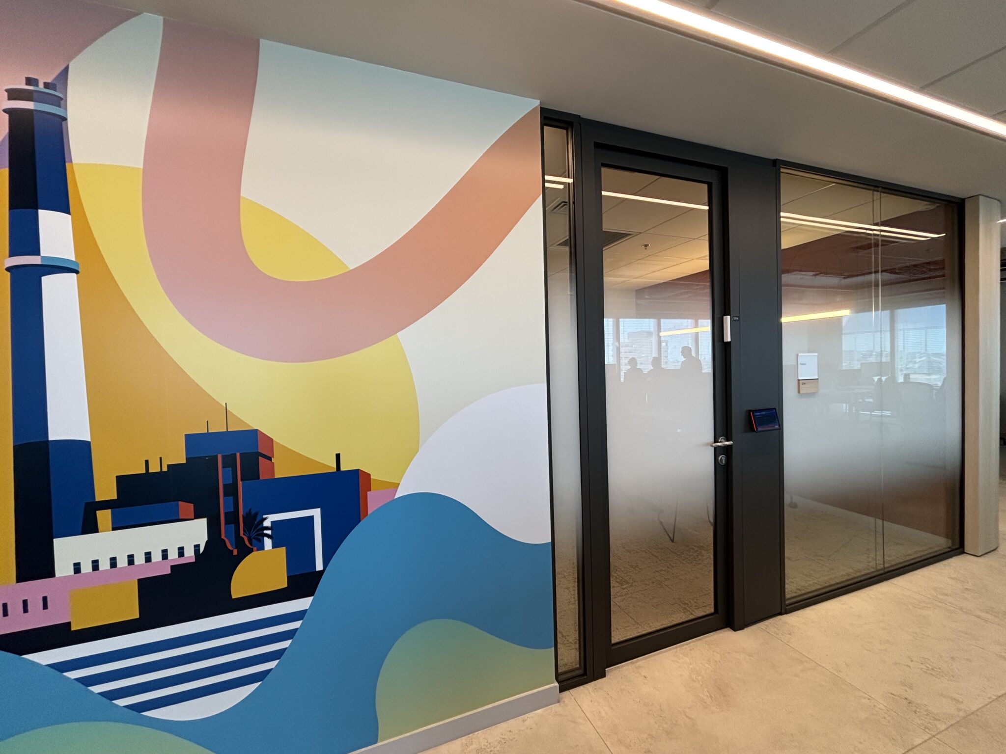 Colourful industrial city mural beside a glass meeting room door