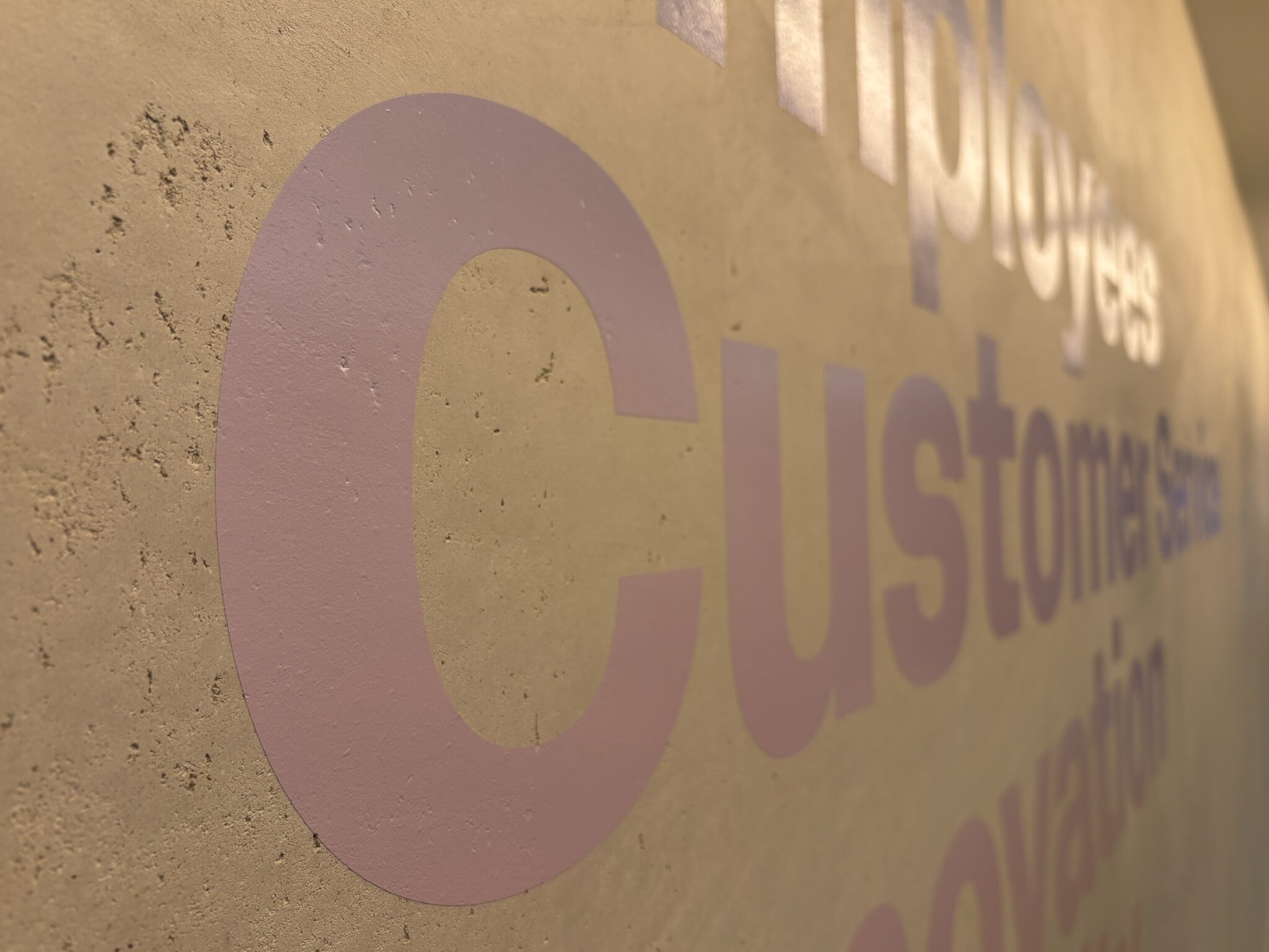 Close-up of pink Customer Service lettering on a stone wall