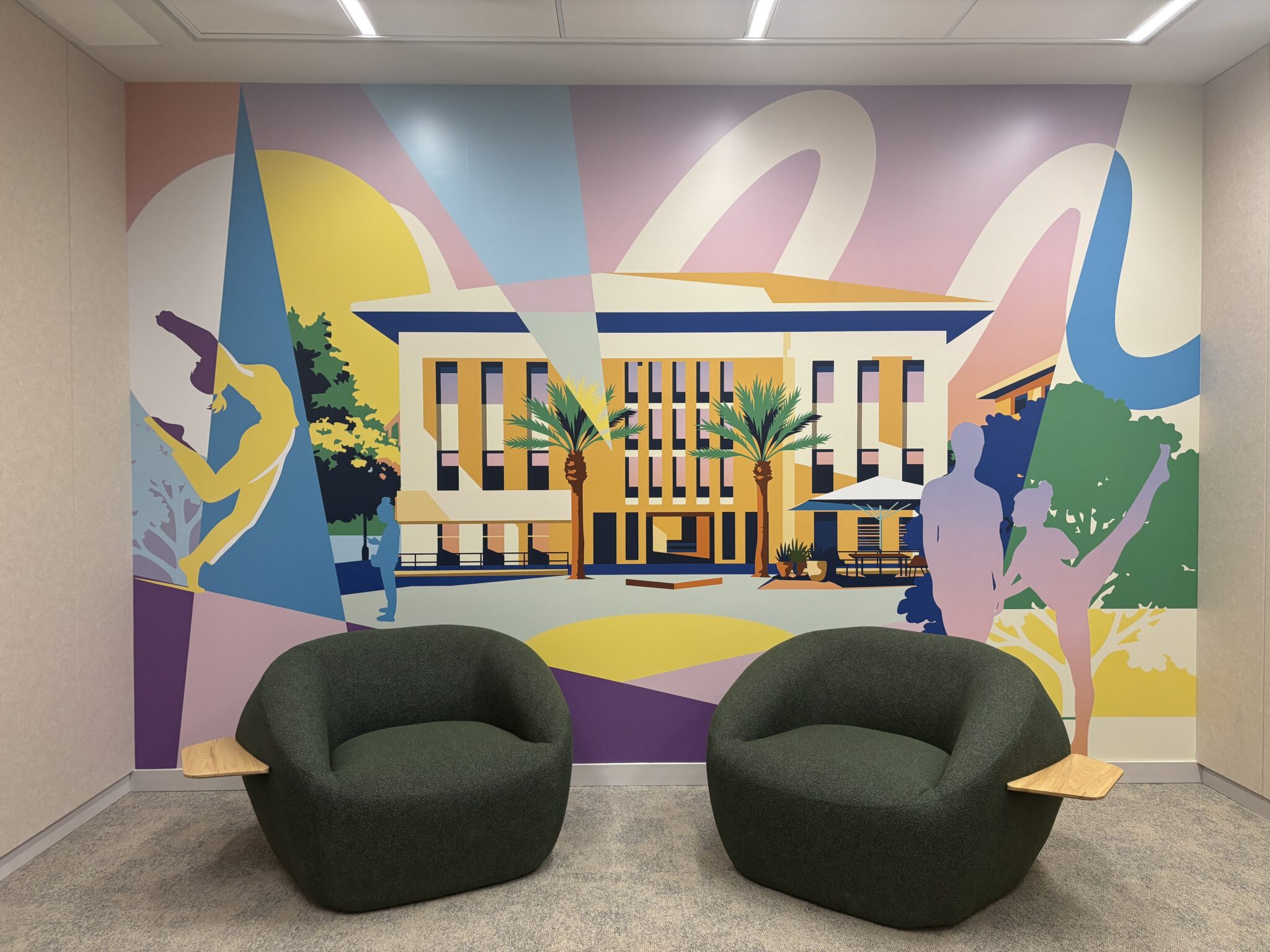 Two green armchairs in front of a colourful city building mural