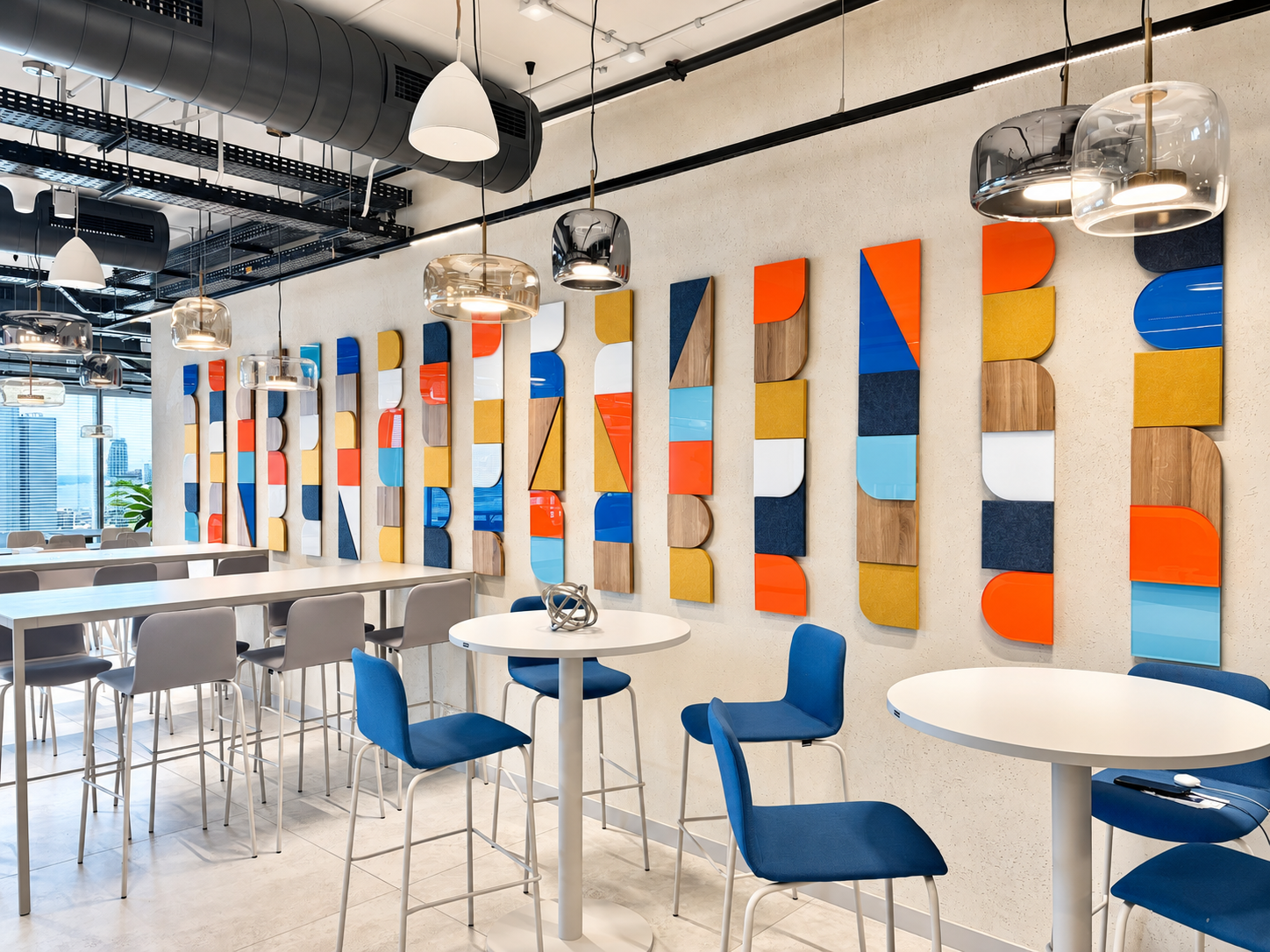 Colourful geometric wall panels behind high tables in a dining area