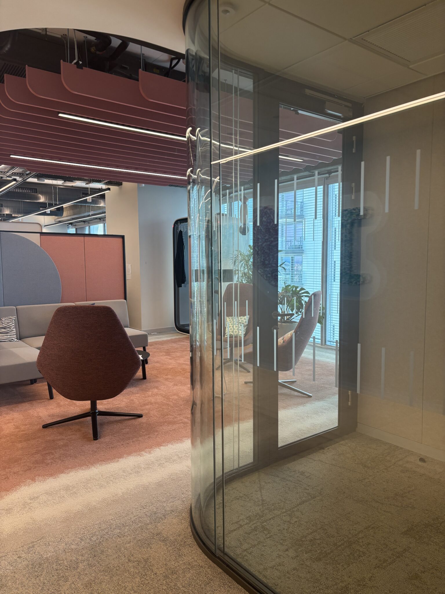Curved glass wall onto a lounge with a brown armchair