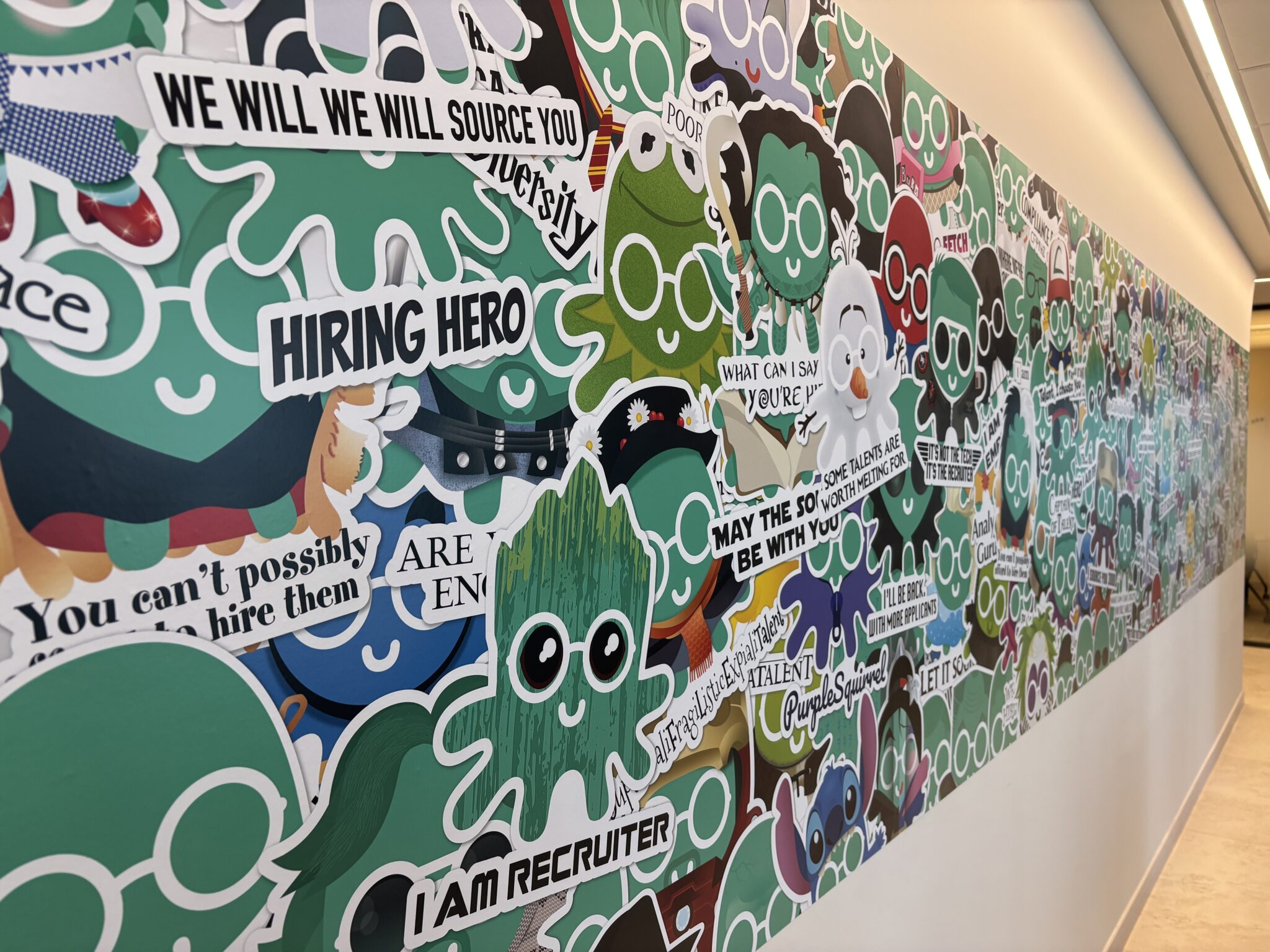 Long wall of green cartoon character stickers with recruiting slogans
